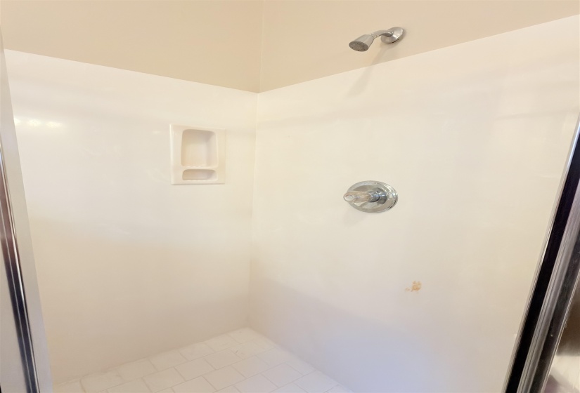 Shower stall with white wall panels and white tile flooring