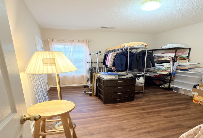 Room featuring wood-finish flooring, a single window with blinds, and a flush-mount ceiling light