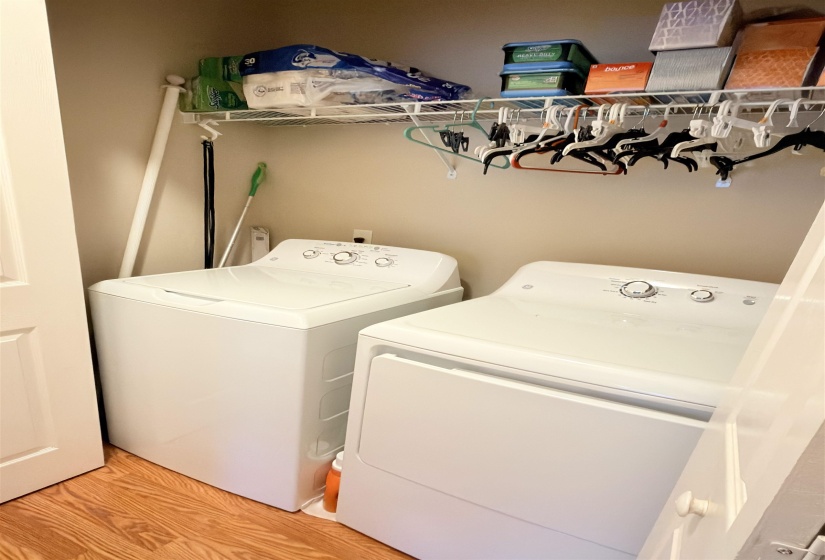 Dedicated laundry area featuring wood-finish flooring, a wire shelving system, and a garment hanging rod
