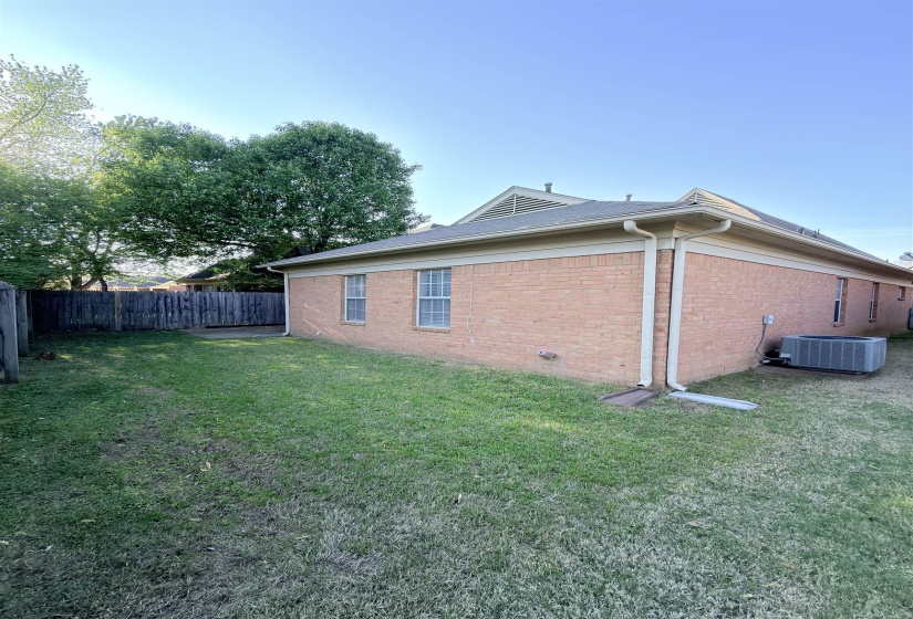 Fenced backyard featuring a brick exterior and a concrete patio pad