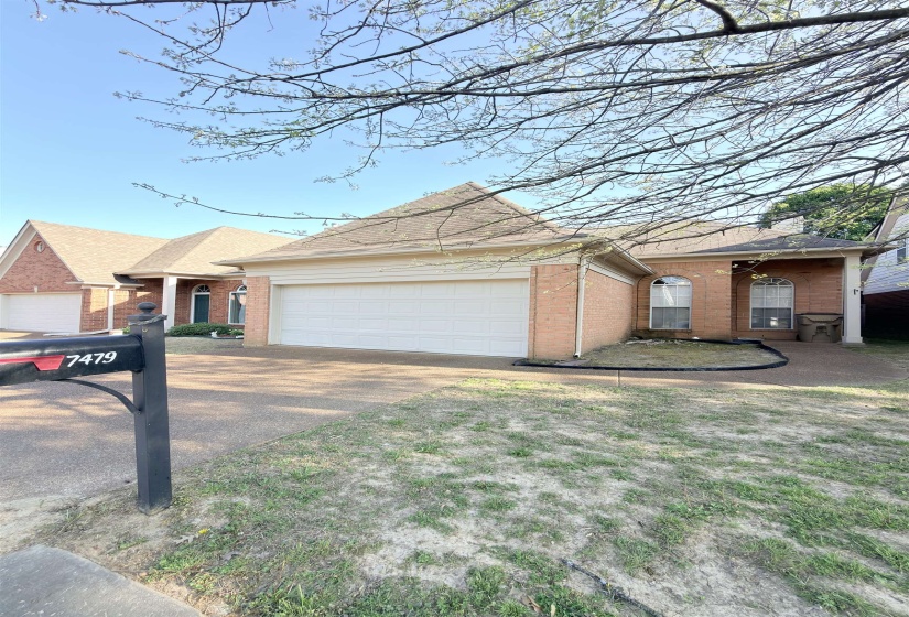 Brick exterior with a multi-gabled roofline, featuring a two-car garage and a paved driveway
