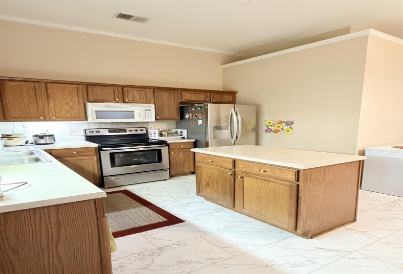 Kitchen featuring wood cabinetry, stainless steel appliances, a center island with countertop, and light-toned tile flooring