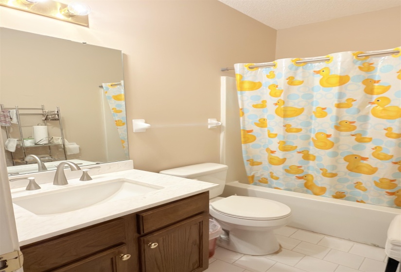 Bathroom featuring a wood-finish vanity with a light-toned countertop, an integrated sink, and a brushed nickel faucet