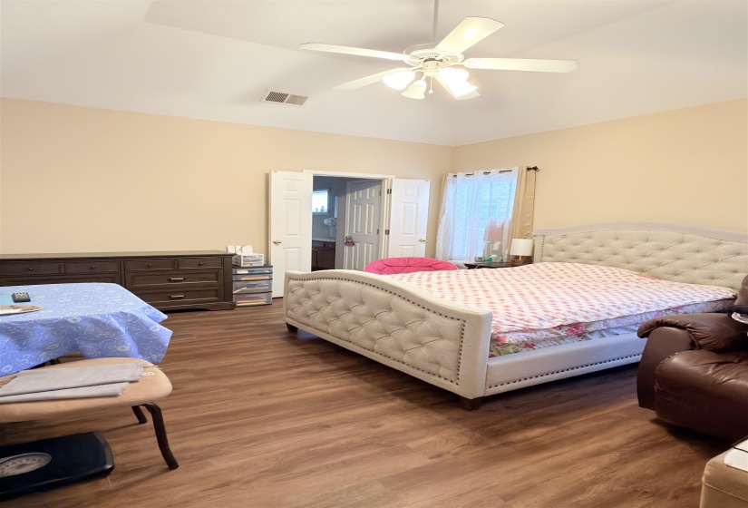 Spacious interior room featuring a tray ceiling, ceiling fan with integrated lighting, wood-finish flooring, and double French doors