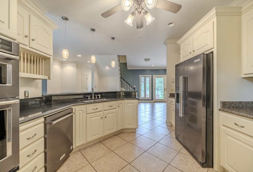 Kitchen featuring cream-colored cabinetry, stainless steel appliances, dark countertops, and tile flooring
