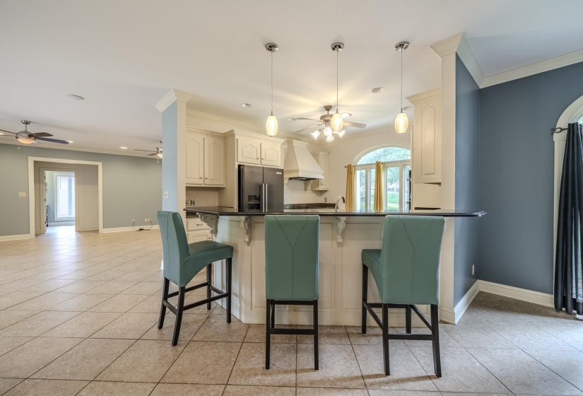 Kitchen featuring a multi-level breakfast bar with a dark countertop, cream-toned cabinetry, and black appliances
