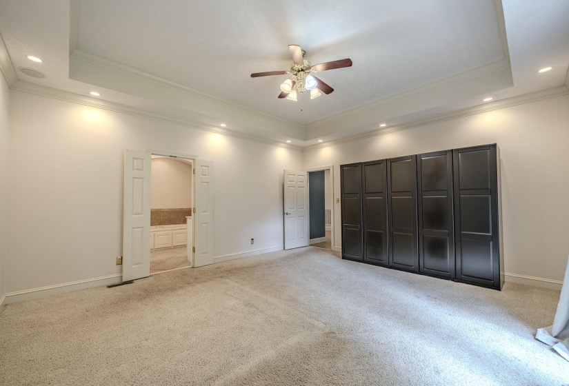 Spacious room featuring a tray ceiling with recessed lighting and a ceiling fan