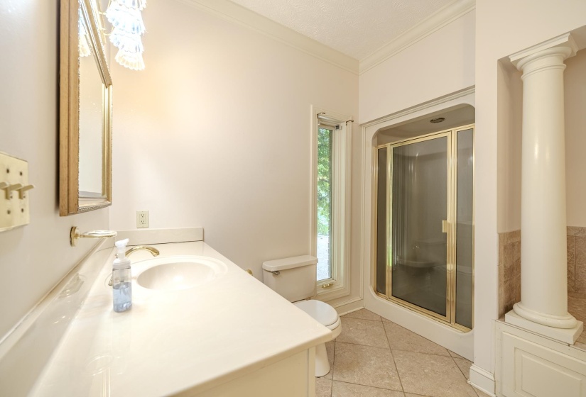 Bathroom featuring a built-in shower with glass enclosure, single vanity with integrated sink, tile flooring, and a decorative column