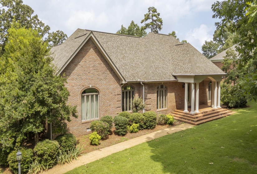 Brick exterior with a gabled roofline, featuring a covered entry porch with white columns and tiered brick steps