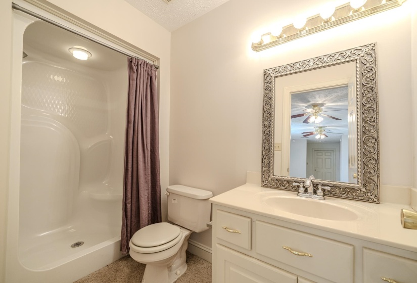 Bathroom featuring a single-piece shower unit with integrated lighting, a white toilet, and a vanity with a drop-in sink