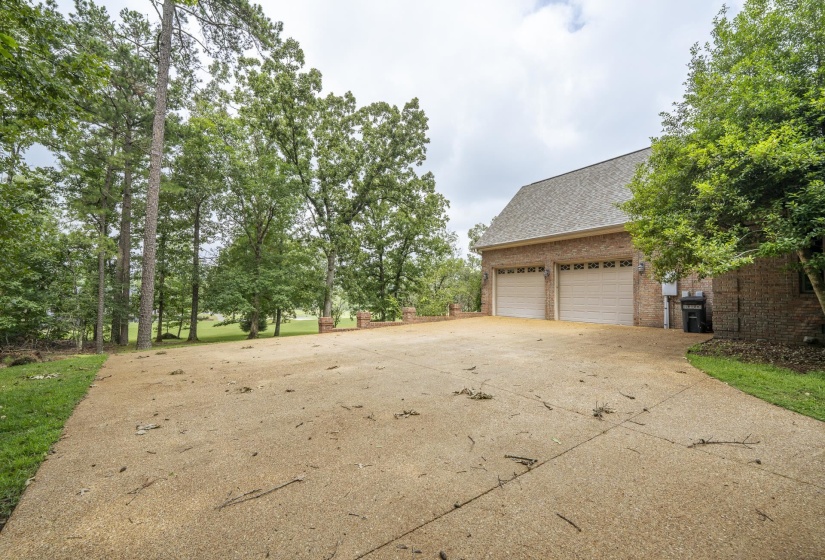 Brick exterior with two garage bays featuring white paneled doors, set against a backdrop of mature trees