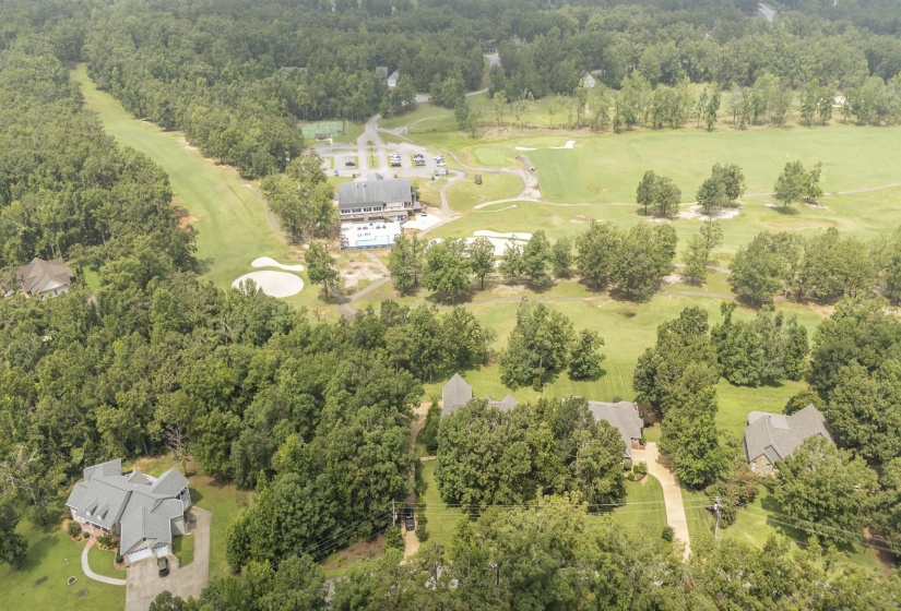 Aerial perspective showcasing a residential area bordered by expansive green spaces and wooded terrain