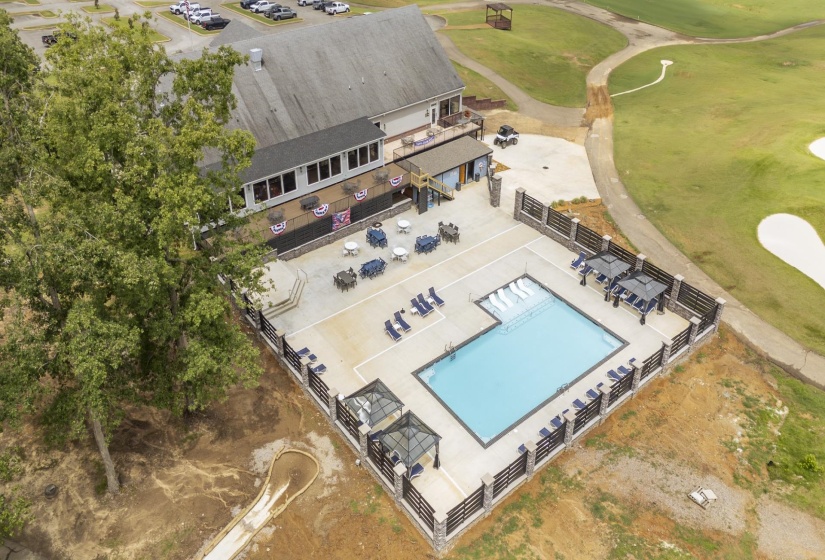 Outdoor swimming pool with surrounding patio, fenced perimeter, and nearby building with an outdoor deck