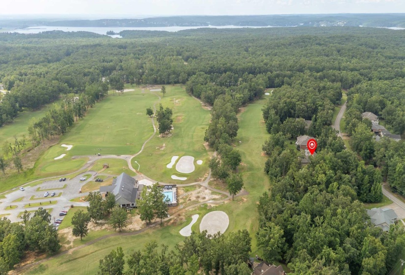 Aerial depiction of a residential property surrounded by mature trees, positioned alongside a golf course with multiple greens and sand traps