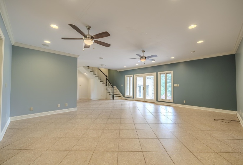 Spacious room featuring light-colored square tile flooring, recessed ceiling lighting, and two ceiling fans