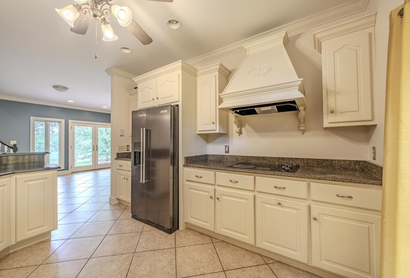 Kitchen featuring white cabinetry, granite countertops, an ornate range hood, and tile flooring