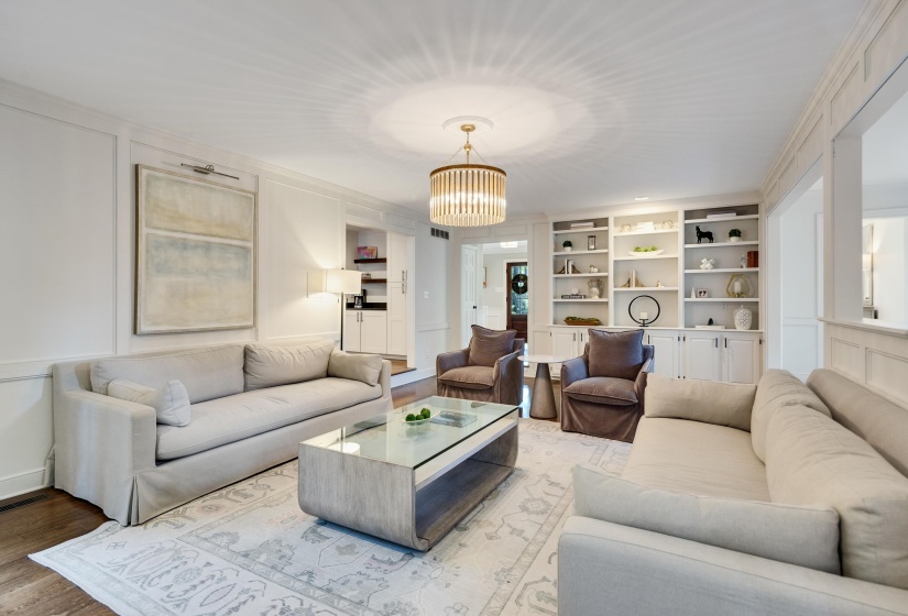 Living area featuring recessed lighting, a decorative chandelier, light-toned wall paneling, and wood-finish flooring