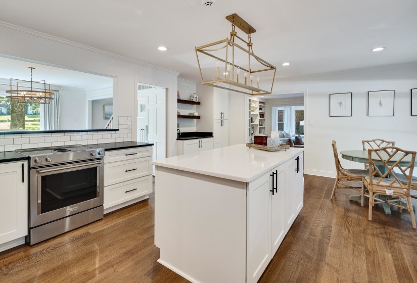 Gourmet kitchen featuring a central island with a solid surface countertop, stainless steel range, white subway tile backsplash, dark-finish perimeter countertops, and wood-finish flooring