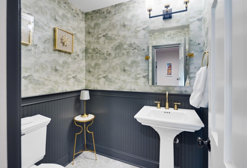 Bathroom featuring a pedestal sink with brass-finish fixtures, a rectangular mirror, and a contemporary vanity light