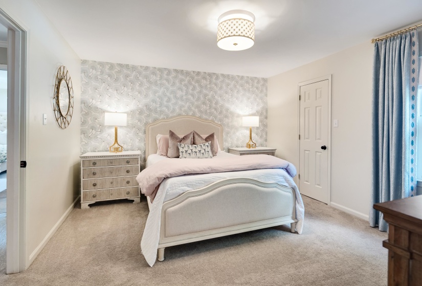 Bedroom featuring a patterned accent wall, neutral carpet flooring, and a flush-mount ceiling light