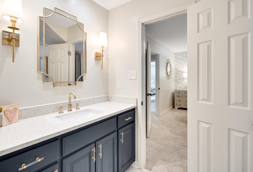 Bathroom vanity with a white countertop and undermount sink, brass-finish faucet, and coordinating wall sconces
