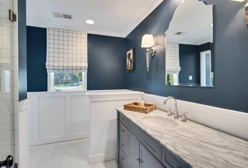 Bathroom featuring a white wainscoting, dark blue walls, and a white penny tile floor