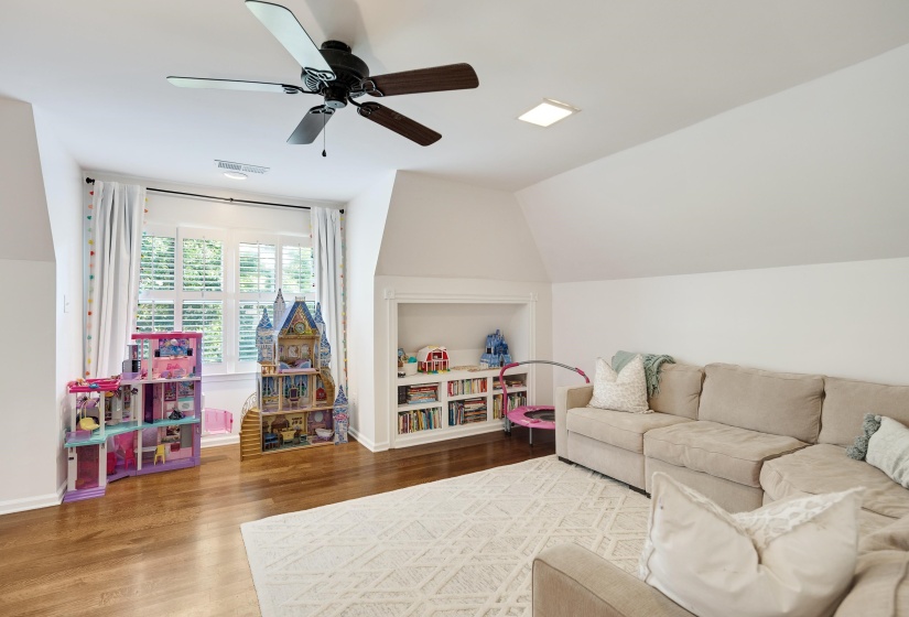 Spacious room featuring hardwood flooring, a ceiling fan, window with plantation shutters, an integrated wall niche with shelving, and a recessed ceiling light