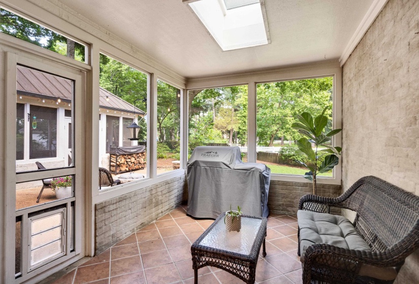 Screened porch with brick wall accents, terracotta-style floor tiles, and a skylight