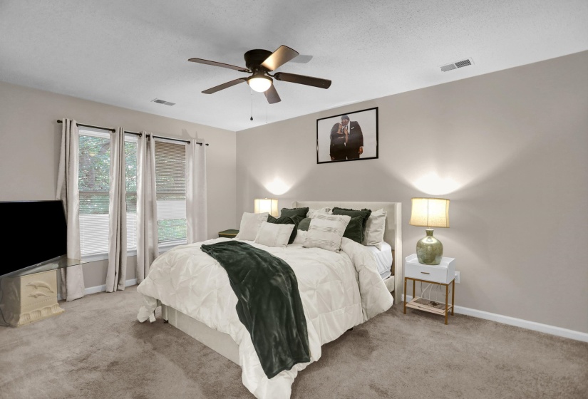 Carpeted room featuring a ceiling fan with integrated lighting, three windows with blinds and curtains, and neutral wall tones