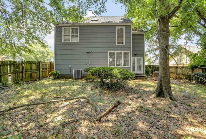 Fenced backyard featuring mature trees and a two-story exterior with siding