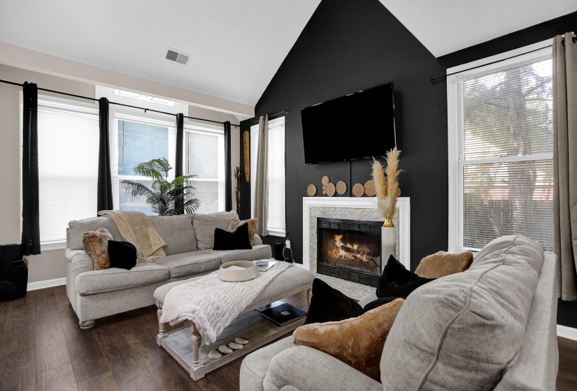 Living area featuring wood-finish flooring, vaulted ceiling, and multiple windows