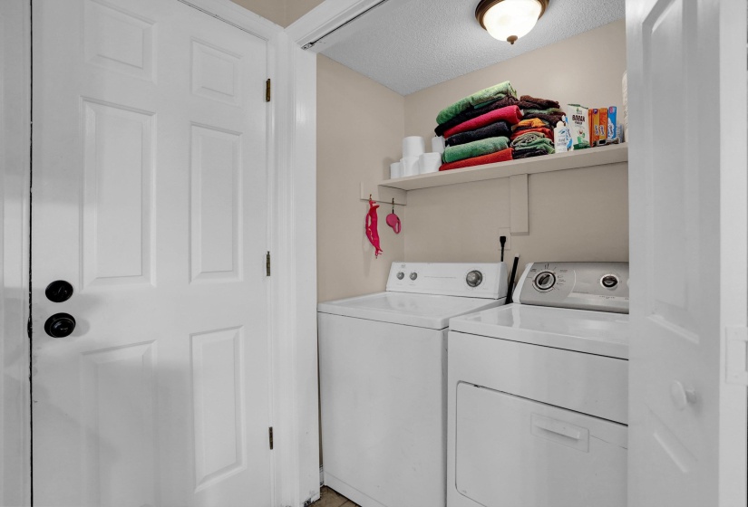 Dedicated laundry area with built-in shelving, a ceiling-mounted light fixture, and white painted walls