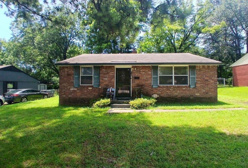 Brick exterior home featuring a dark gray roofline, multiple windows, and a front entry with a security screen door