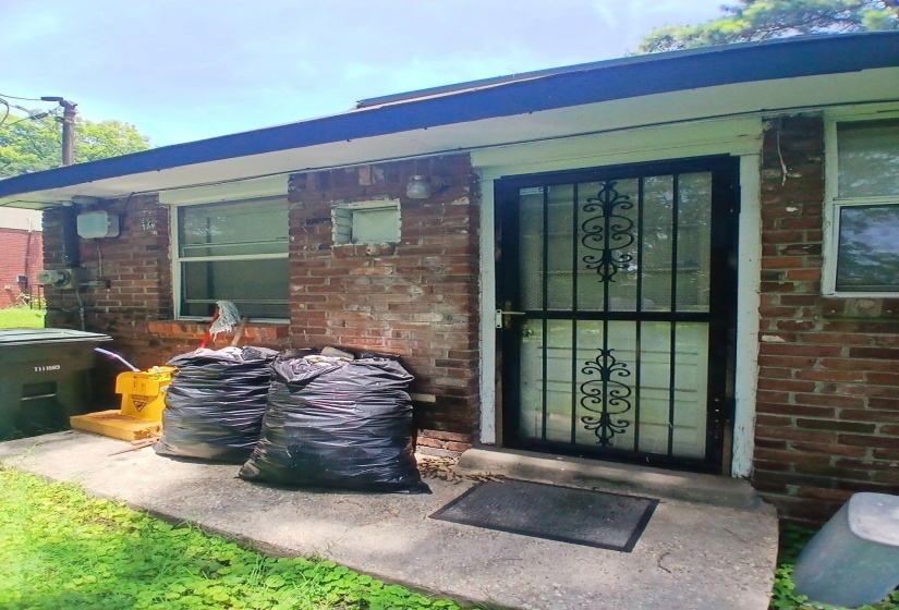 Brick exterior featuring multiple windows and a metal security screen door