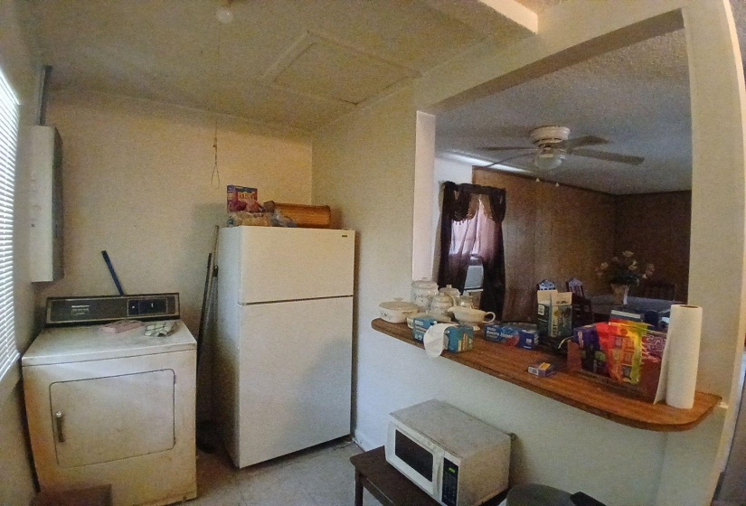 Kitchen area featuring a built-in wood-finish counter with an open pass-through, a ceiling-mounted light fixture, and textured ceilings