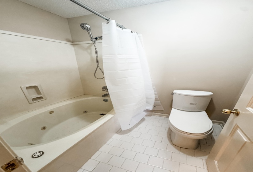 Shower-over-jetted-tub combination with a wall-mounted toilet