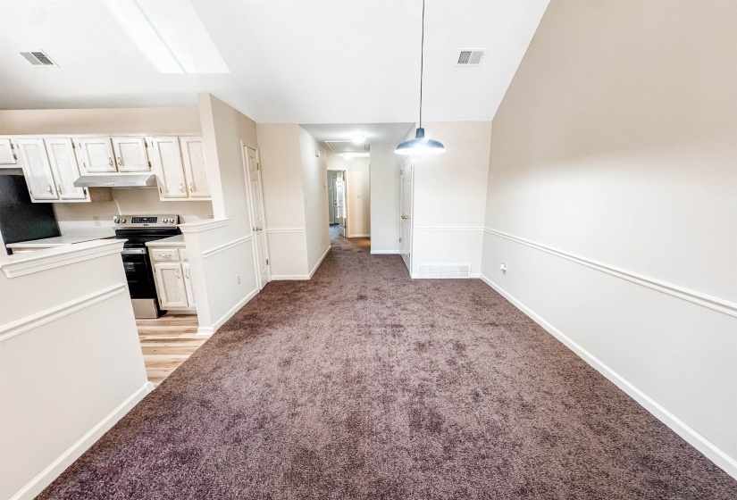 Open-concept living space featuring neutral wall tones, decorative wainscoting, and a distinct pendant light fixture