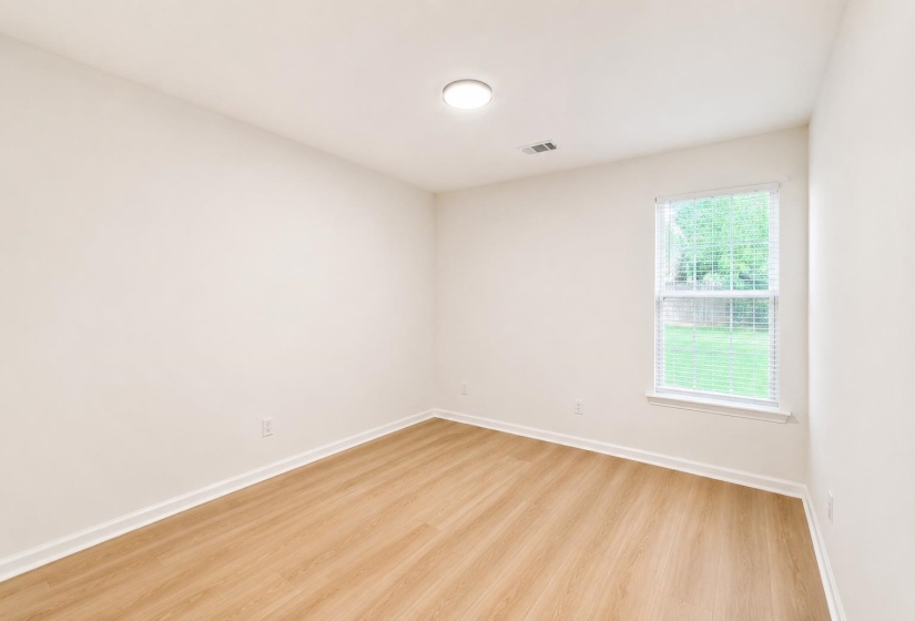 Light-filled room featuring wood-finish flooring, white baseboards, and a single window with blinds