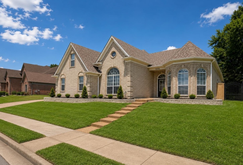 Light-colored brick exterior featuring arched windows, a front entry with a small portico, and dormer windows