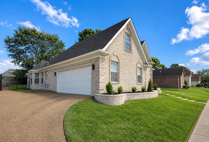 Light-colored brick exterior featuring a white garage door, gabled roofline, and dormer windows