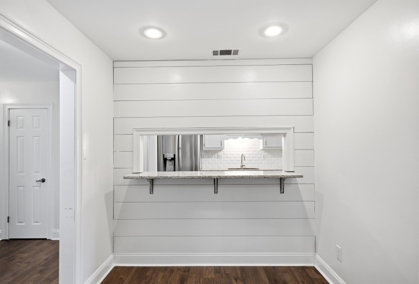 Pass-through window with a granite countertop, shiplap accent wall, recessed lighting, wood-finish flooring, and white trim