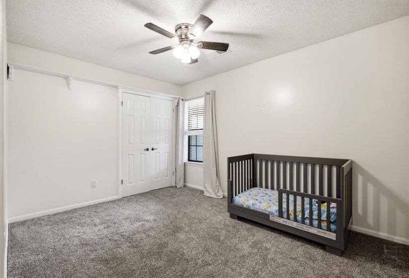 Spacious room featuring neutral carpeting, a ceiling fan with integrated lighting, and a window with blinds