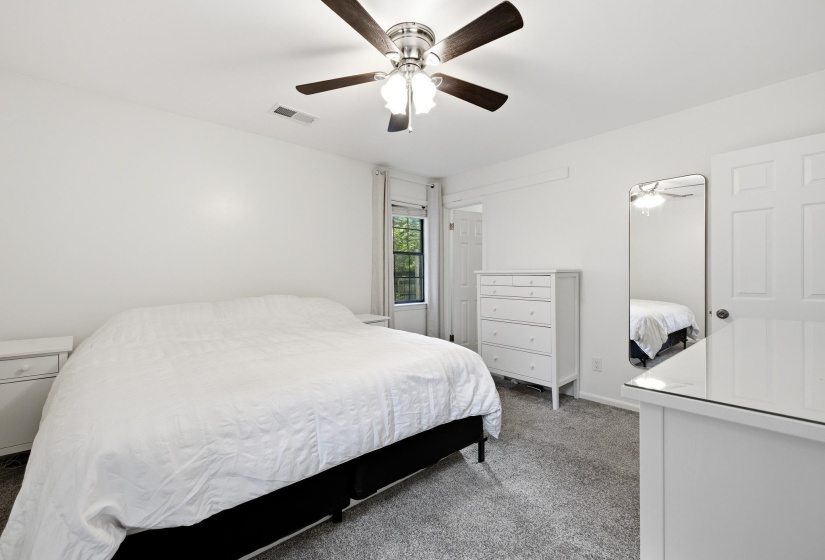 Carpeted room featuring a ceiling fan with light fixture, white walls, and a window with blinds