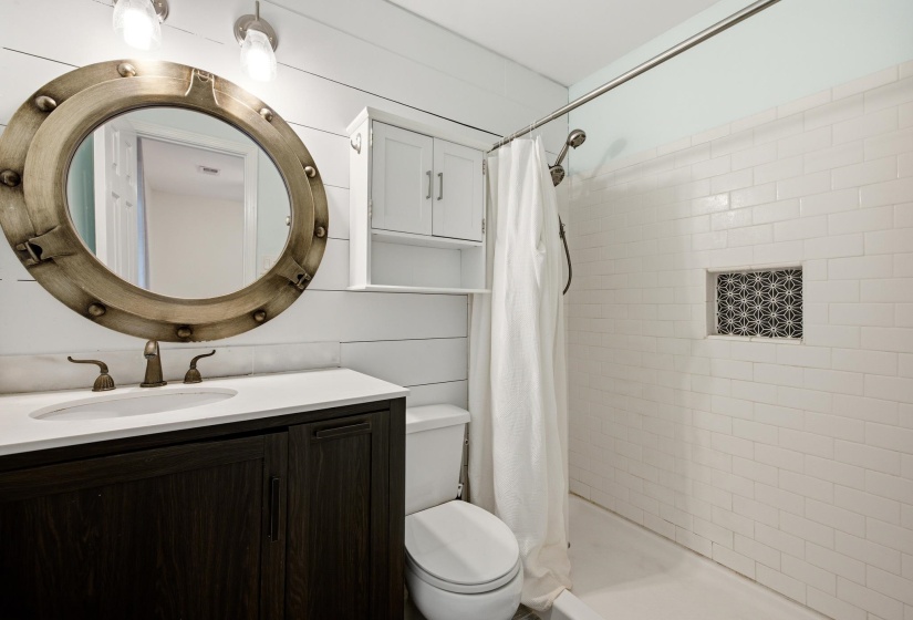 Vanity with an integrated sink, bronze-finish faucet, and a circular mirror with riveted detailing