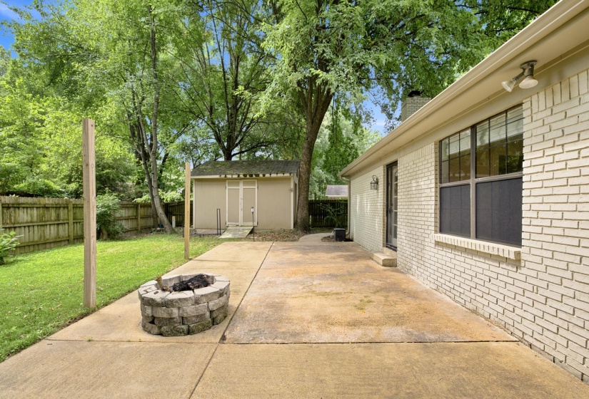 Spacious concrete patio featuring a stone fire pit