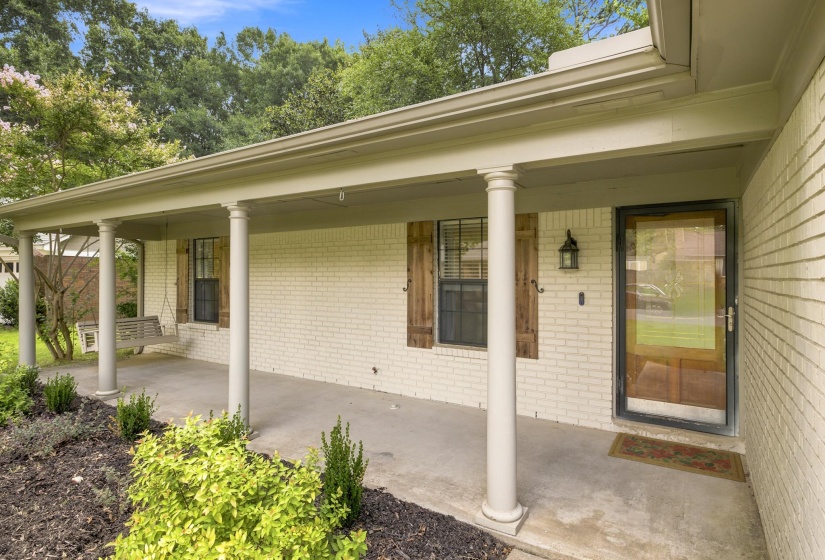 Inviting covered front porch with white brick exterior and architectural columns