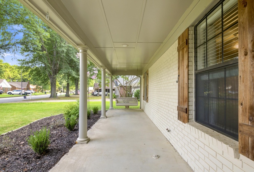 Expansive covered porch featuring a white brick facade and classic white columns