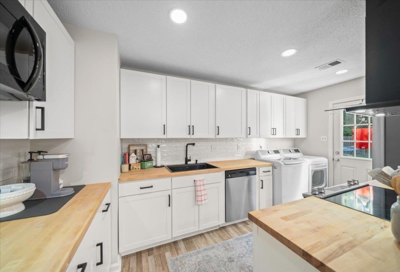 Bright kitchen featuring white shaker cabinetry, wood-finish countertops, stainless steel appliances, and wood-finish flooring