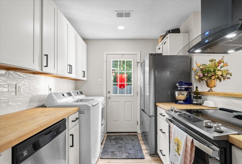 Kitchen featuring white shaker-style cabinetry, wood-finish countertops, subway tile backsplash, stainless steel appliances, and recessed lighting