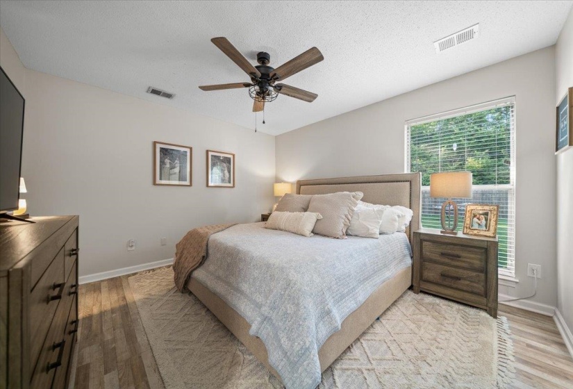 Bedroom featuring wood-finish flooring, a ceiling fan with light fixture, and a window with blinds